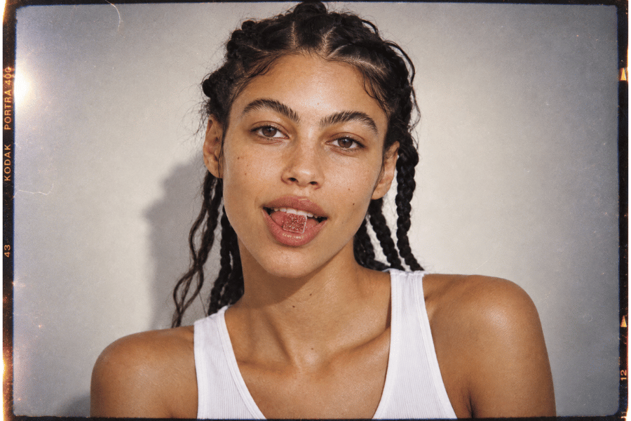 a girl in a white shirt with a gummy in her mouth