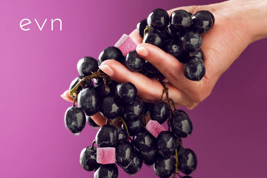 a hand holding grapes and grape gummies