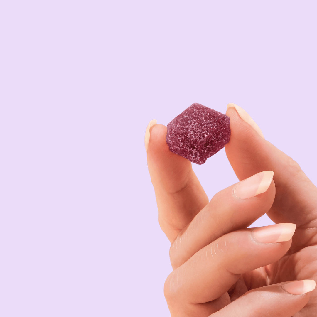 a hand holding a purple gummy