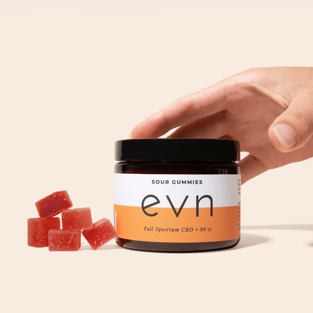 a hand reaching for a cbd gummy jar