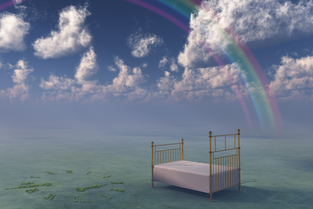 a bed on a body of water with a rainbow in the background