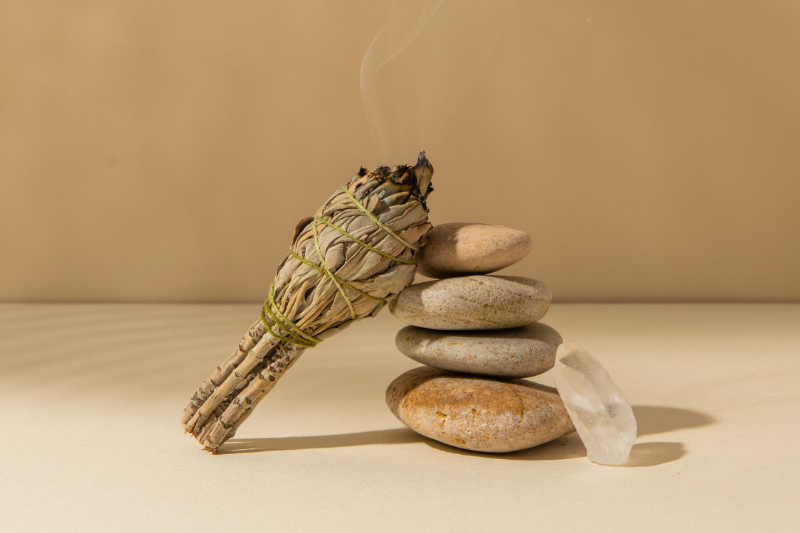 a bundle of sage leaves burning next to stones