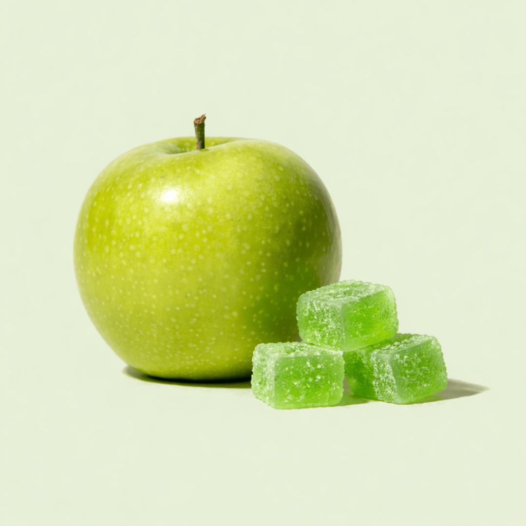 three green gummies next to an apple