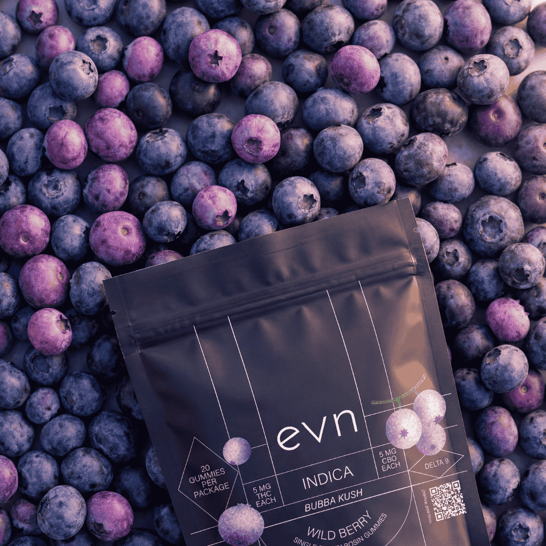 A full frame of blueberries with an EVN indica bubba kush CBDD gummies pouch laying on the top