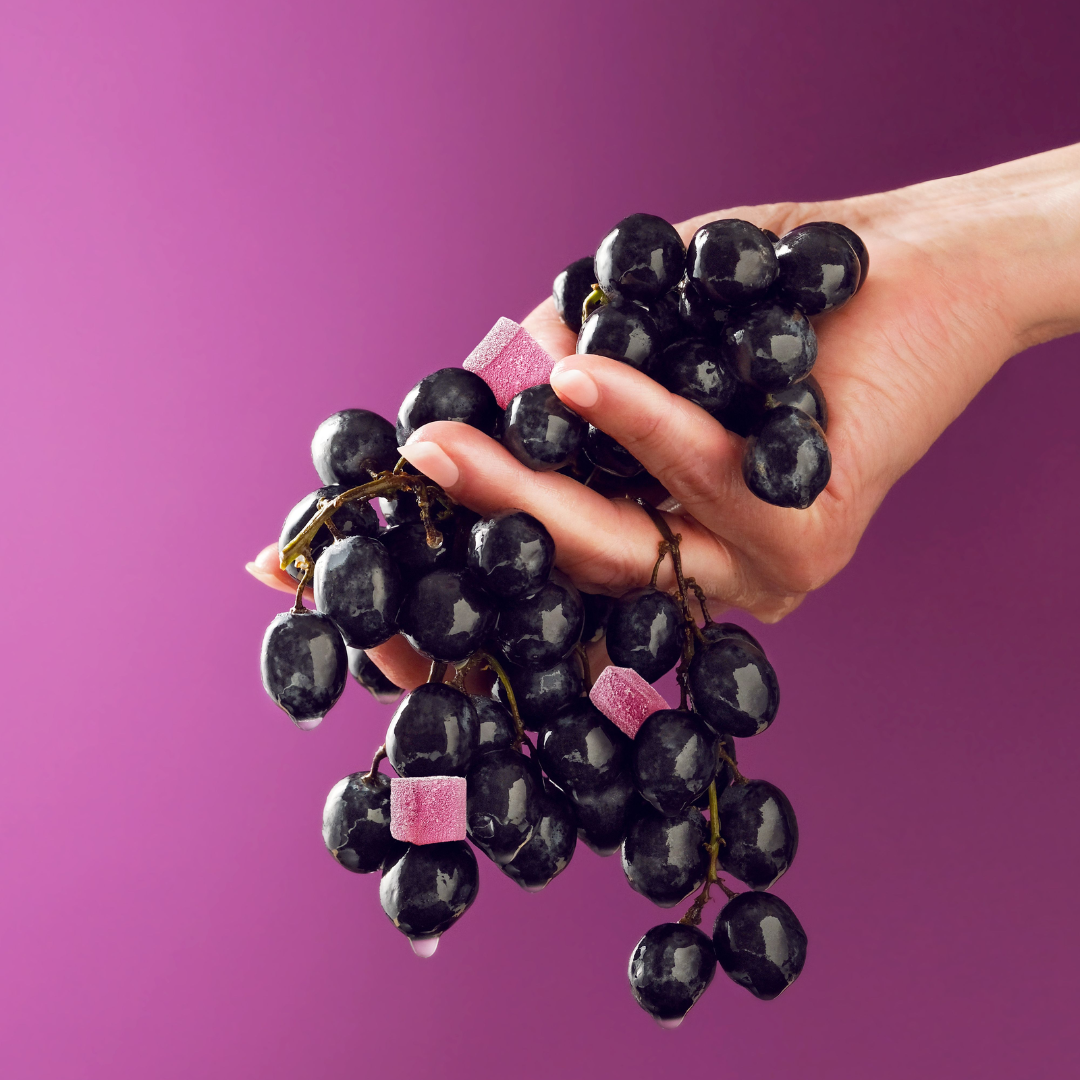hand holding grapes and grape gummies