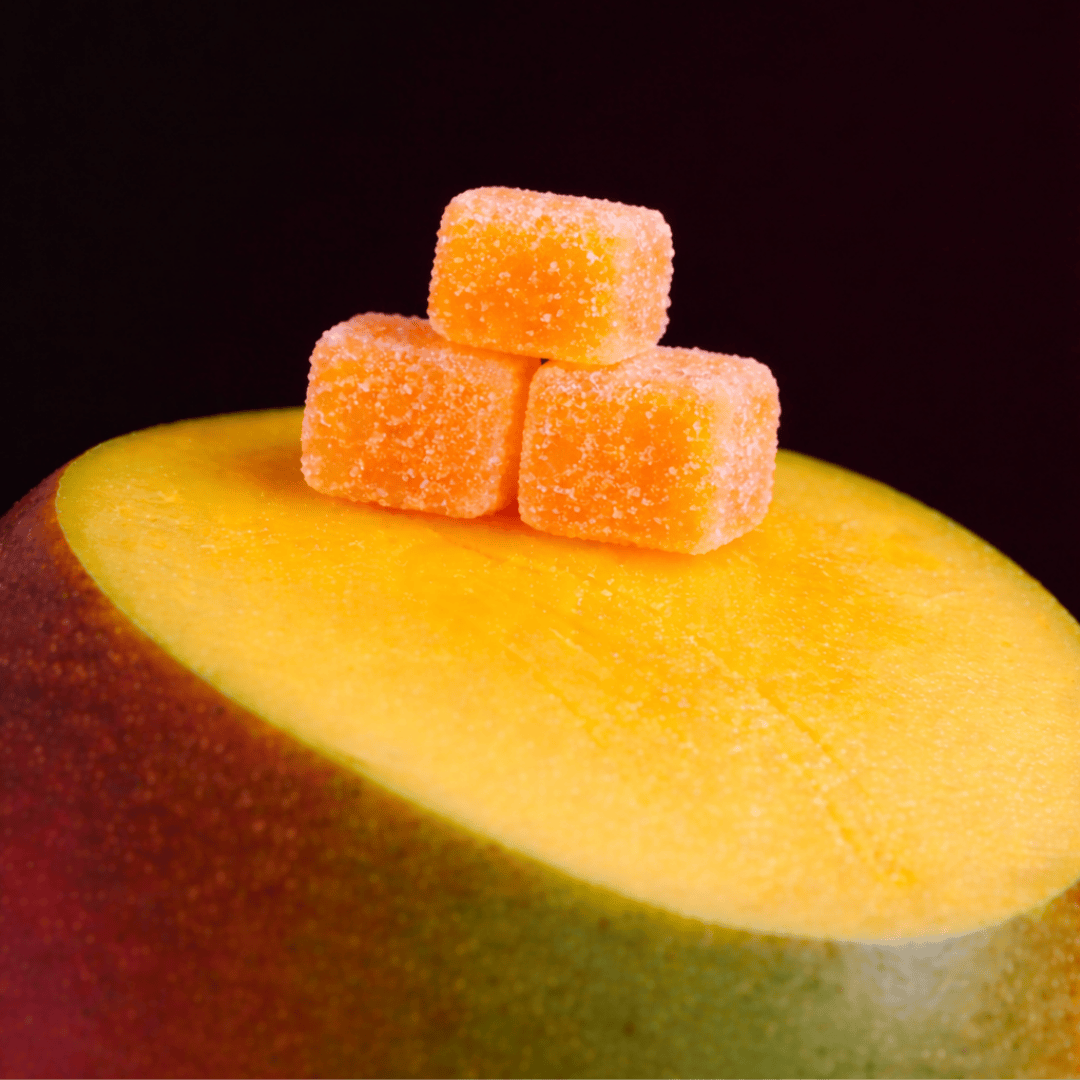 three mango gummies on top of a cut mango