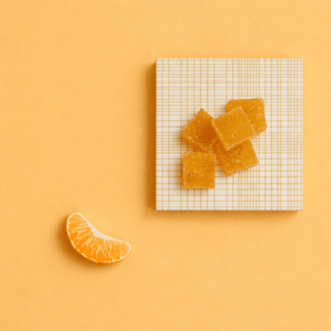 a slice of orange next to orange gummies